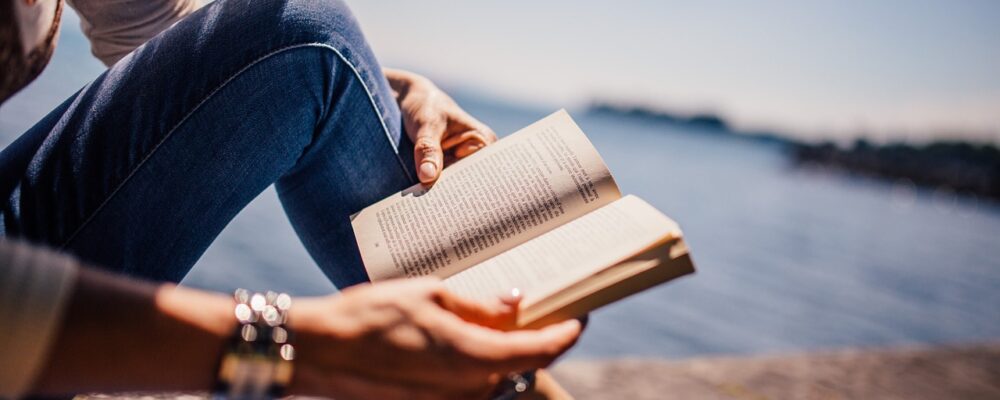 Frau liest ein Buch am Meer