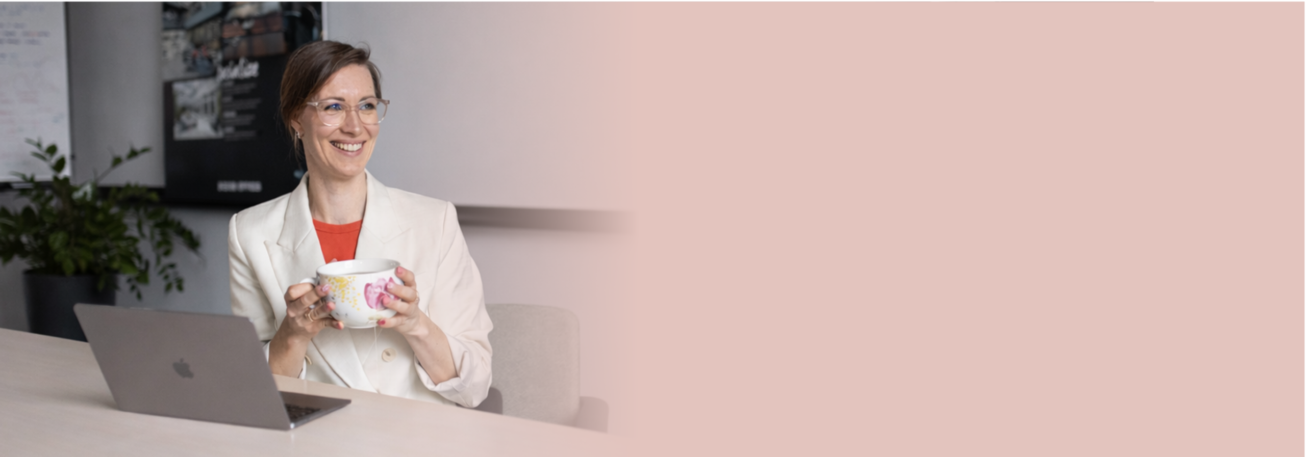 Header-JanineFrank Janine Frank sitzt mit einer großen Tee-Tasse an einem hellen Schreibtisch vor ihrem Laptop und schaut freundlich zur Seite.