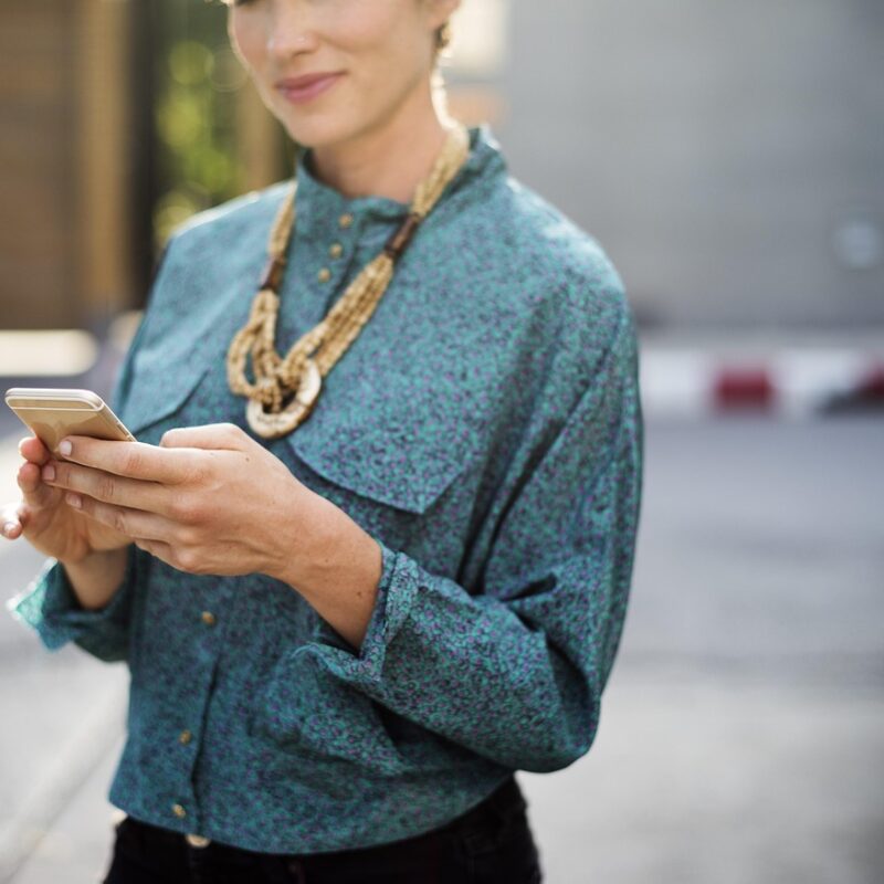Frau mit Handy in der Hand die ihr Online Business aufbaut